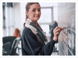 Mujer sonriendo y escribiendo en una pizarra